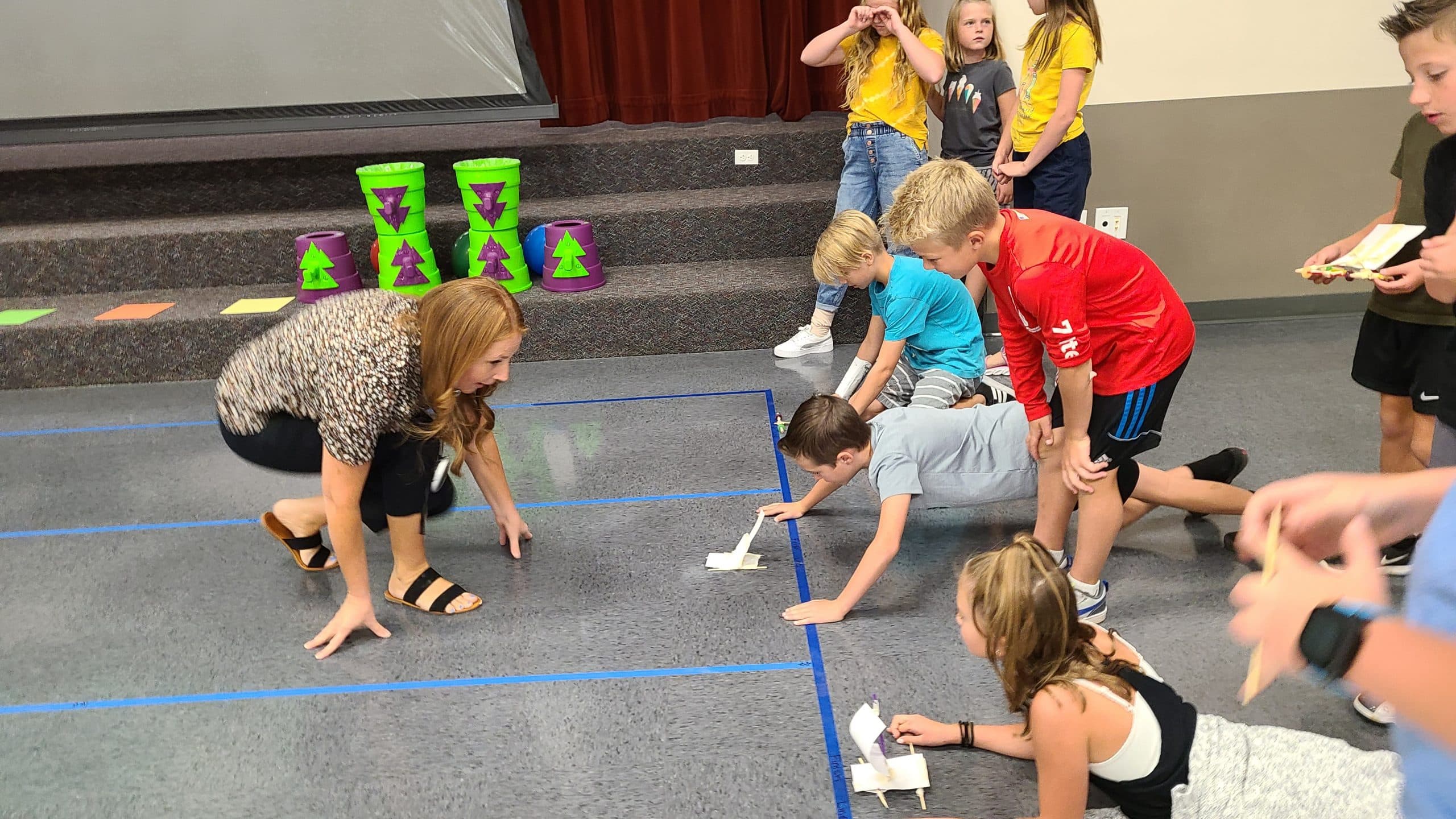 Student having a boat race on the gym floor with a staff member.