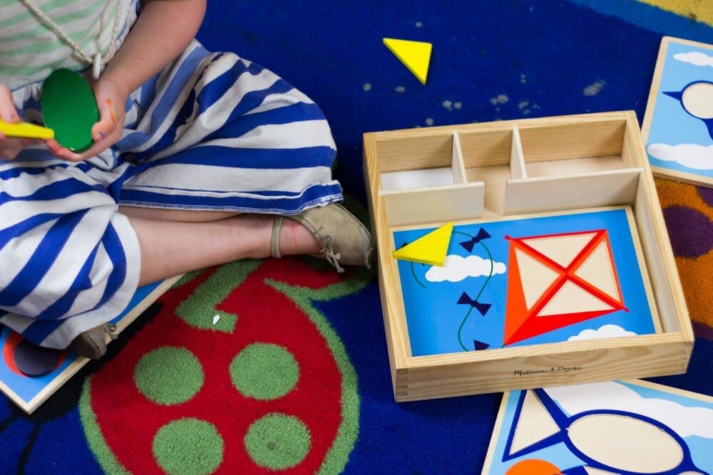 Preschool child completing a colorful shape-matching activity that supports fine motor development
