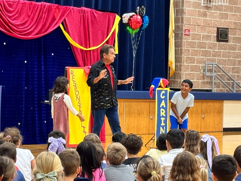 A magician shows off a magic trick with help from students.