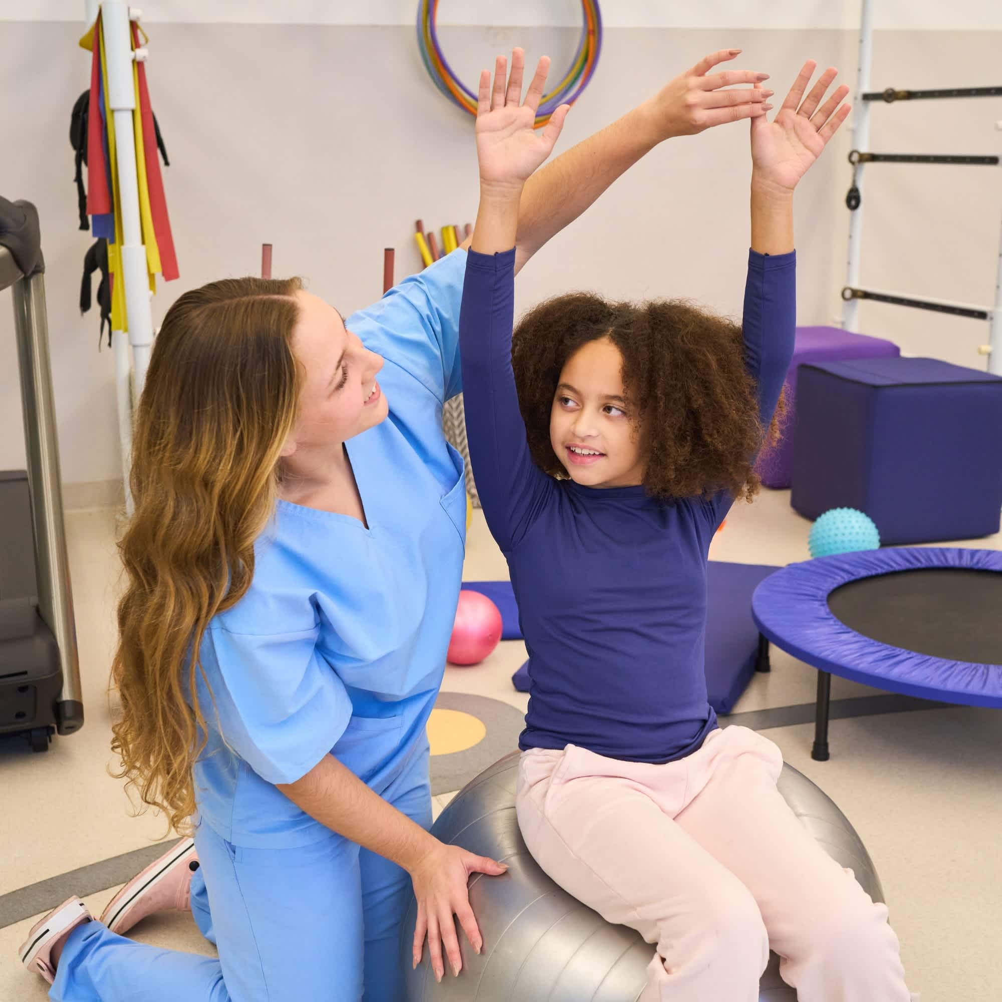 A healthcare worker examines a girl, who is holding her hands above her head.