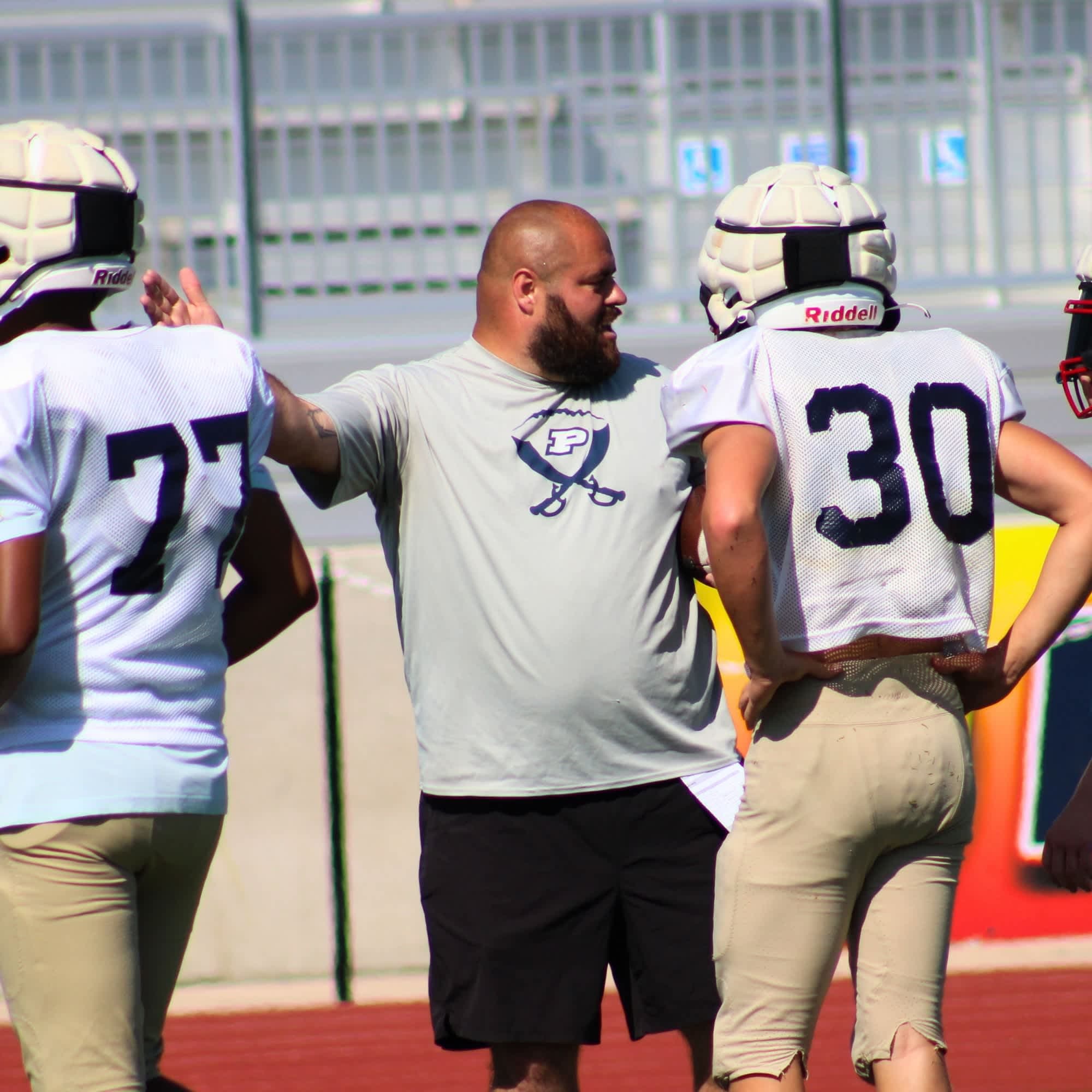 A coach talks to football players.