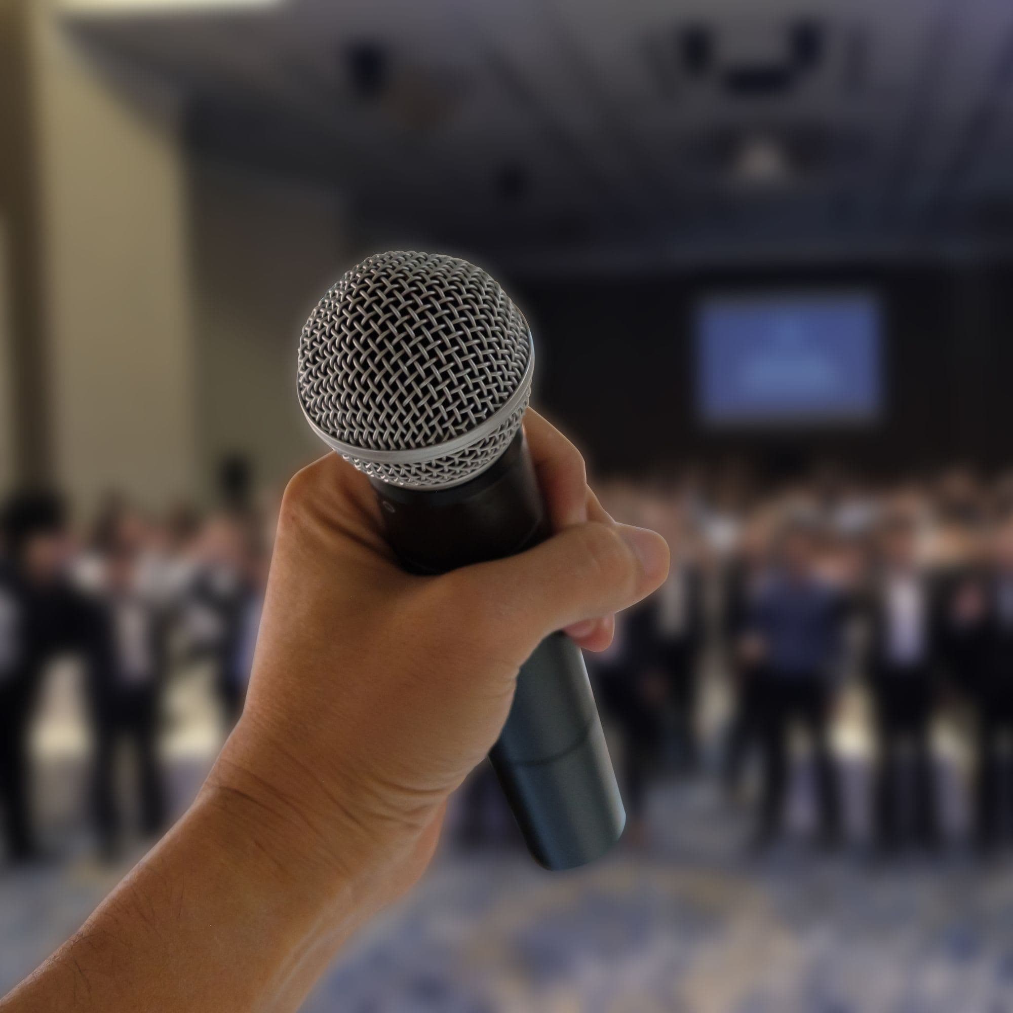 A picture of a microphone being held by a hand.