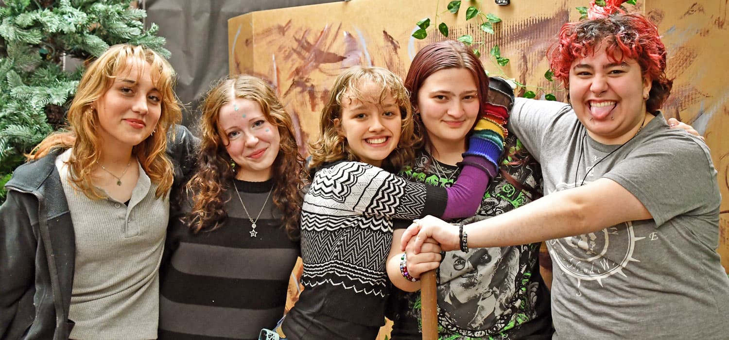 A group of six people stand close together, smiling at the camera.