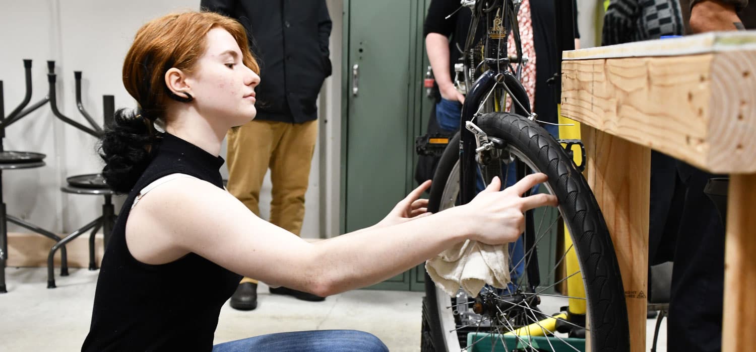 A person with red hair is holding a black object, possibly a steering wheel.