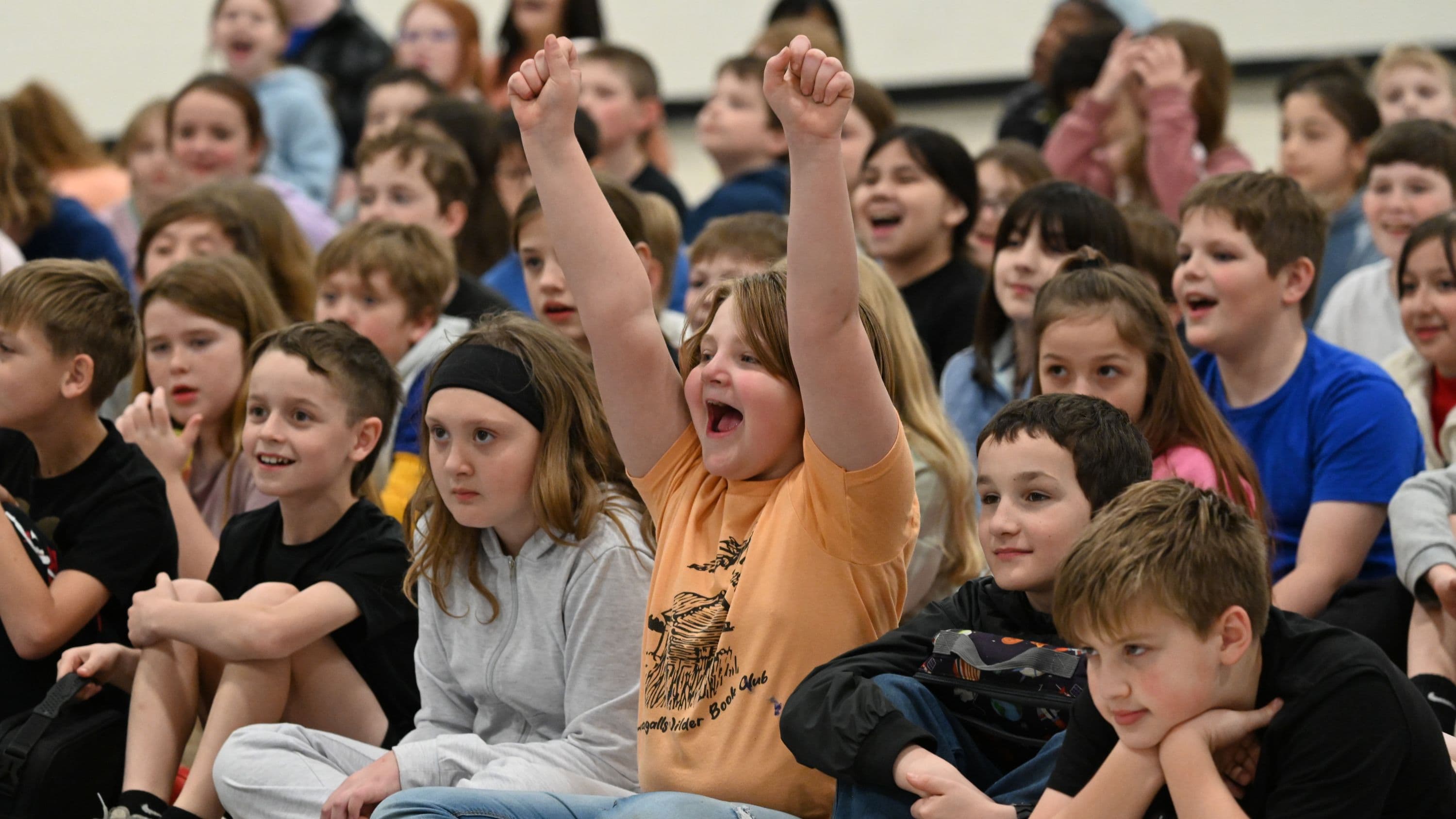 A student cheering at an assembly.