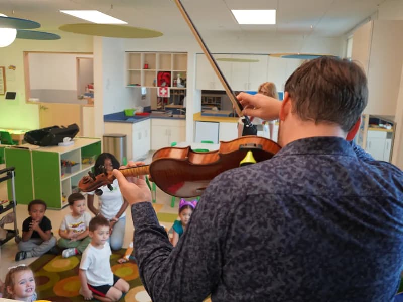 Musician playing violin for preschool children