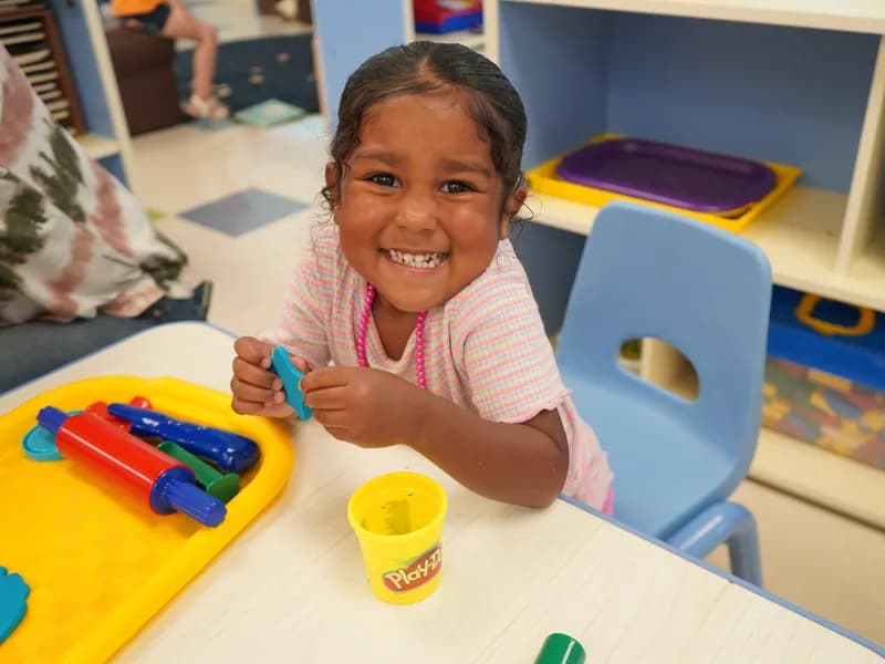 Smiling girl playing with modeling clay