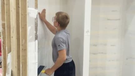 Construction Trades student putting up drywall