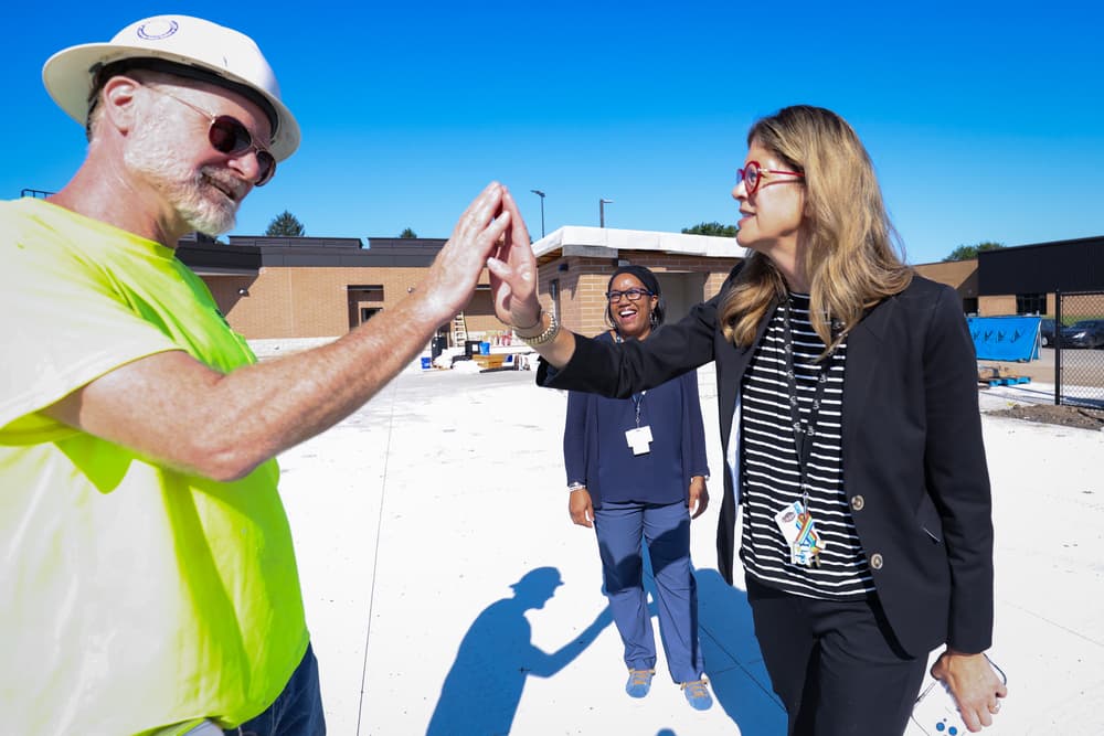 Two adults high five outside of a football field