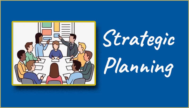 A group of people are gathered around a table in a meeting room, with the words "Strategic Planning Committee" written in large script to the right.