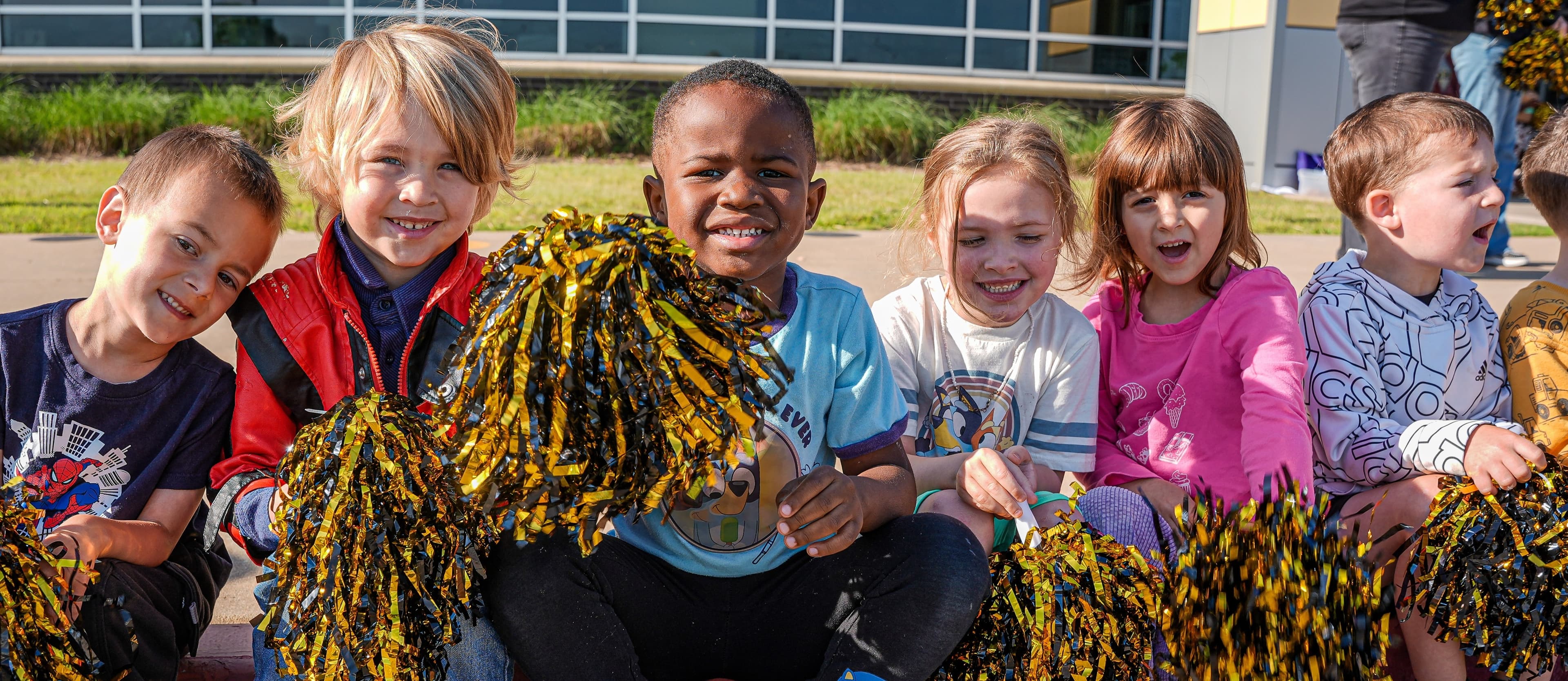 Pre-Kindergarten students sitting in front of their school site.