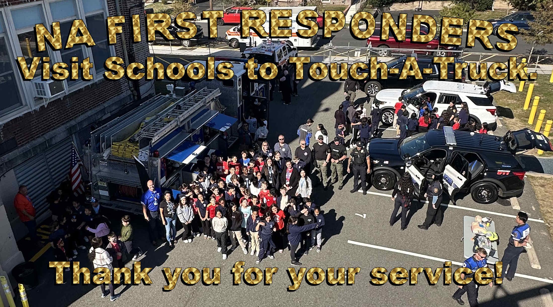 A group of students and first responders gather around emergency vehicles in front of a school building.