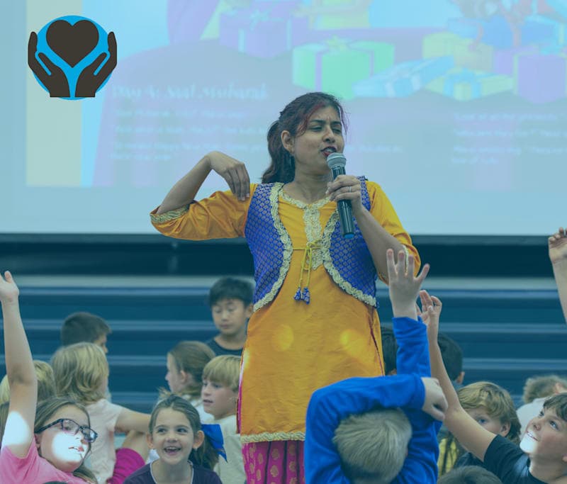 This is an image of a woman speaking to a group of energetic students about the Indian heritage. This woman is dressed in traditional Indian clothing.