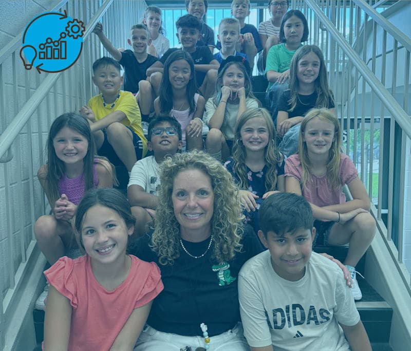 This is an image of students and their teacher posing for a photo on stairs in their school building.