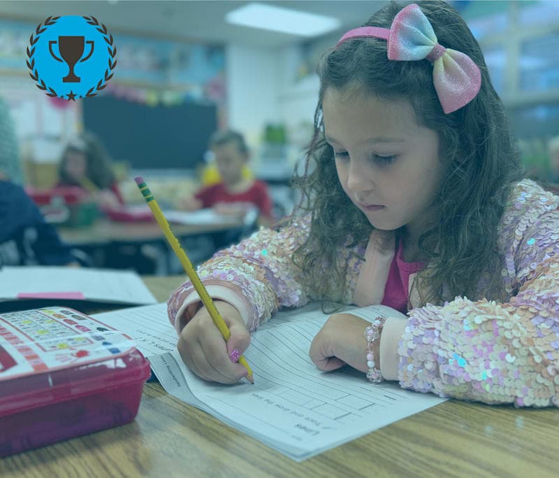 This is an image of a student working on an assignment in class with a pencil on a workbook.