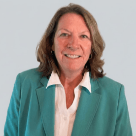 A woman in a teal blazer and white shirt smiles for a formal photo against a white background.