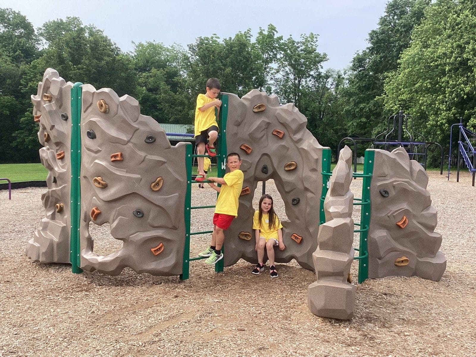 Children playing on a playground and climbing wall.