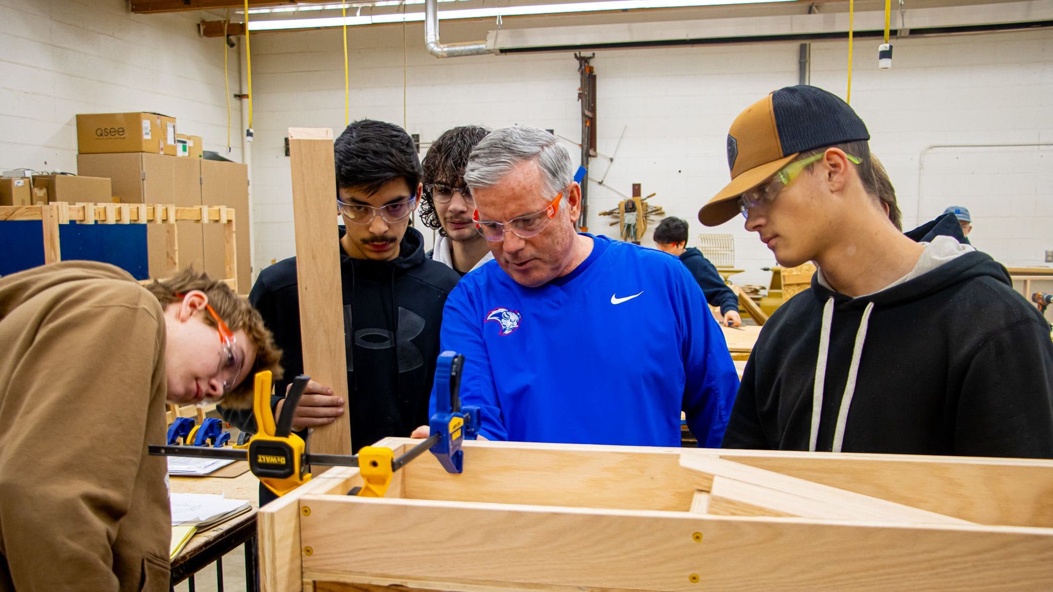 Students and a teacher stand in front of a shelf they're working on in class.
