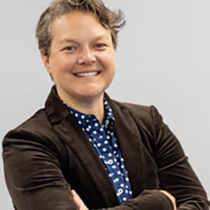 A picture of Meg Murray wearing a suit with her arms crossed.