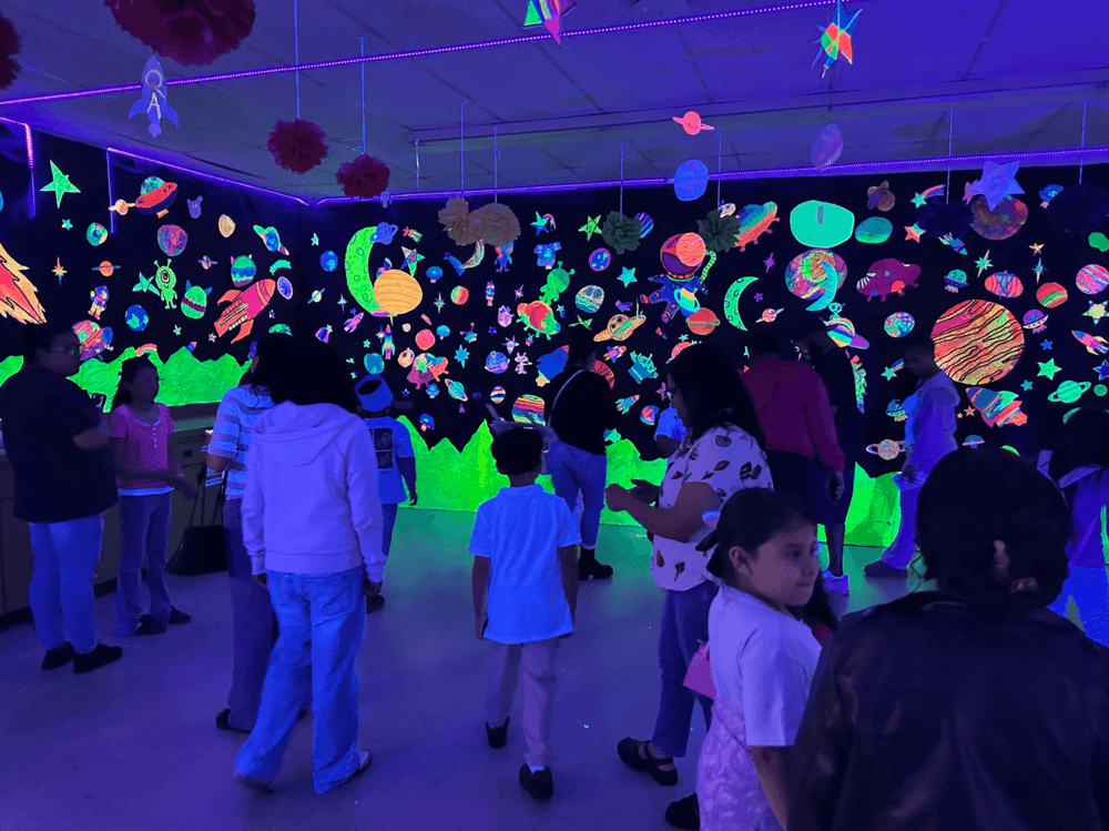Students in a dark room with glowing decorations on the walls
