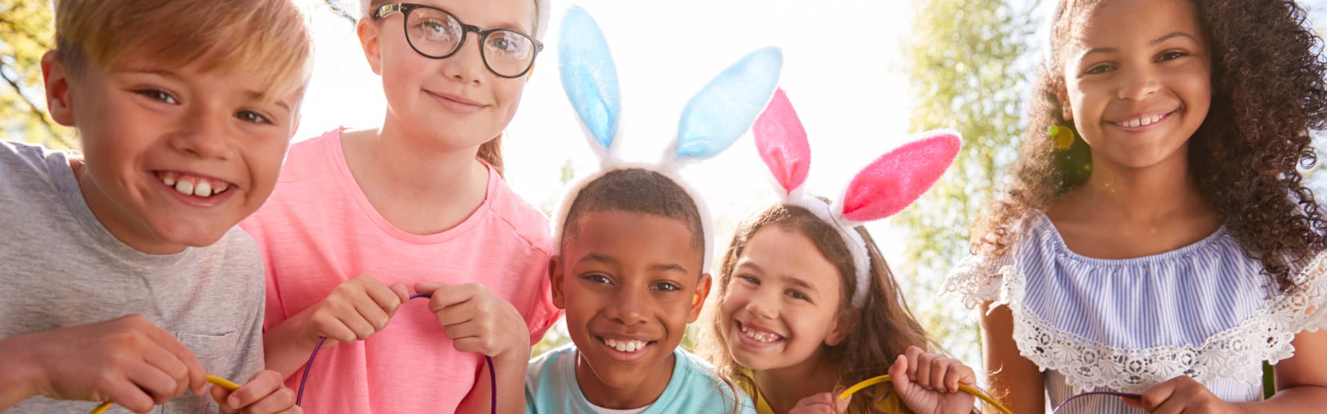 Portrait Of Five Children Wearing Bunny Ears On Easter Egg Hunt In Garden