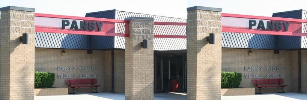 Facade of Pansy Kidd Middle School featuring a prominent sign, entrance, and a small garden with a bench.