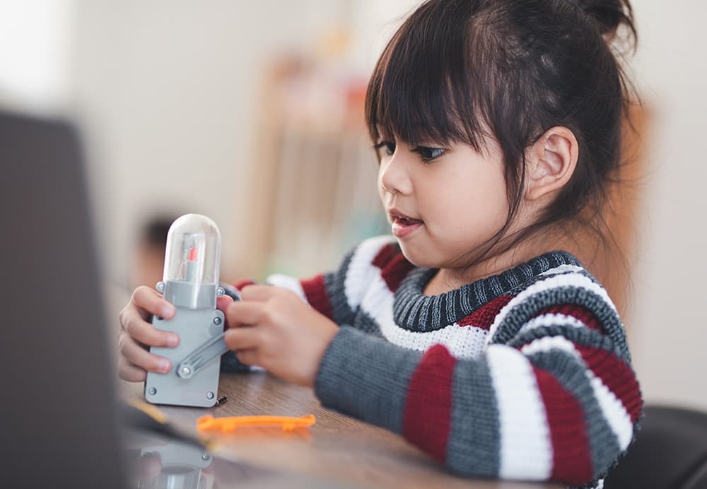A child joyfully engages with a toy, symbolizing a strong foundation for future learning and creativity.