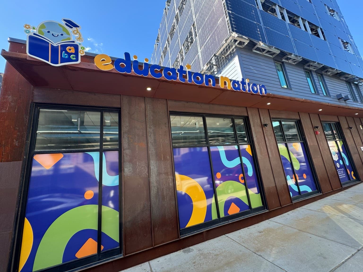 Exterior of ENLA Education Nation daycare with colorful window graphics and entrance sign.