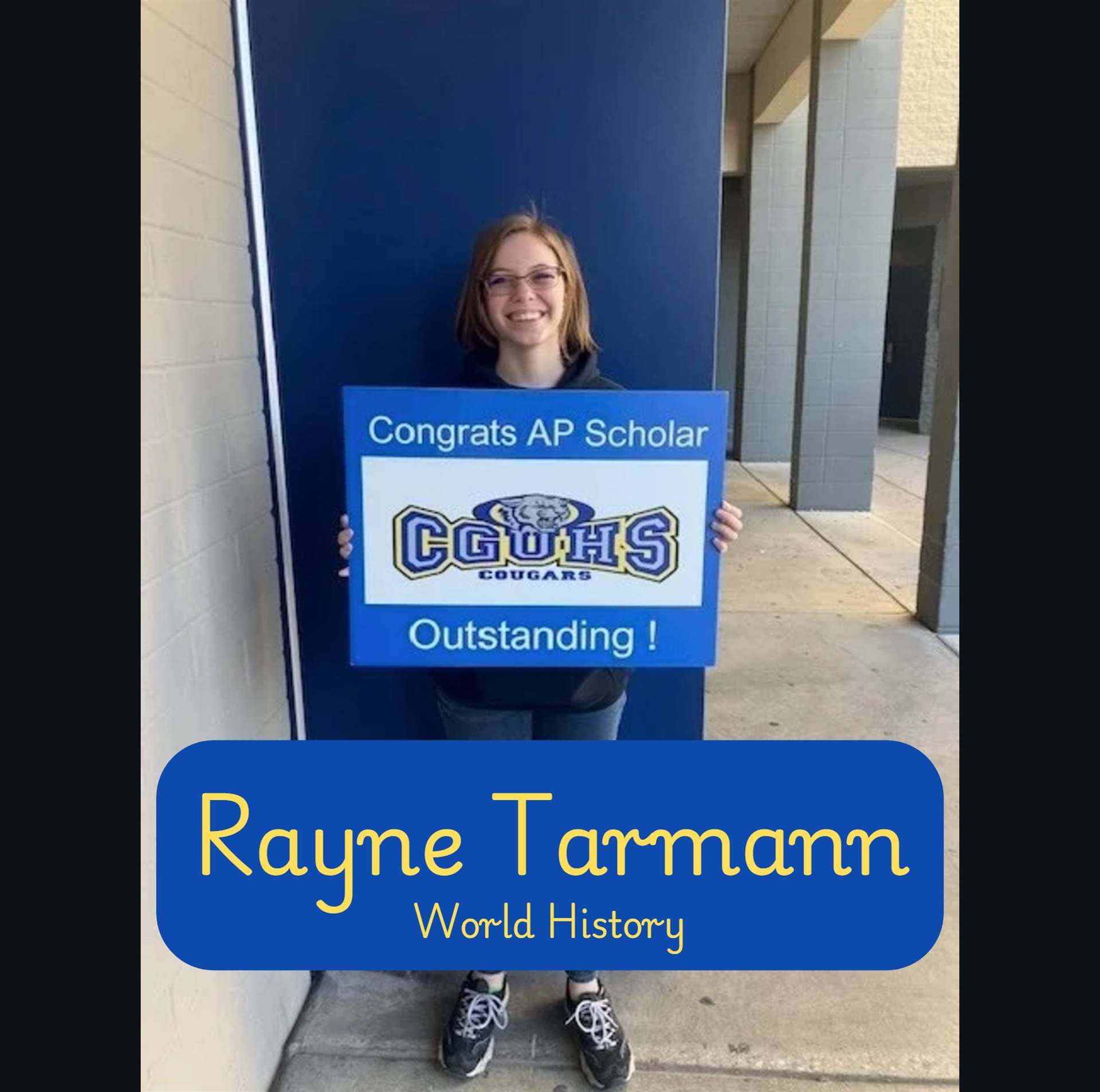 A student named Rayne Tarmann stands outside holding a sign that reads 'Congrats AP Scholar' and 'Outstanding!' with a school logo in the background.