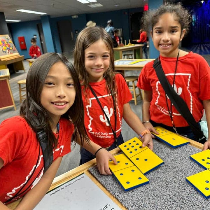3 CTA Independence students smile for a photo while working on a learning project in class