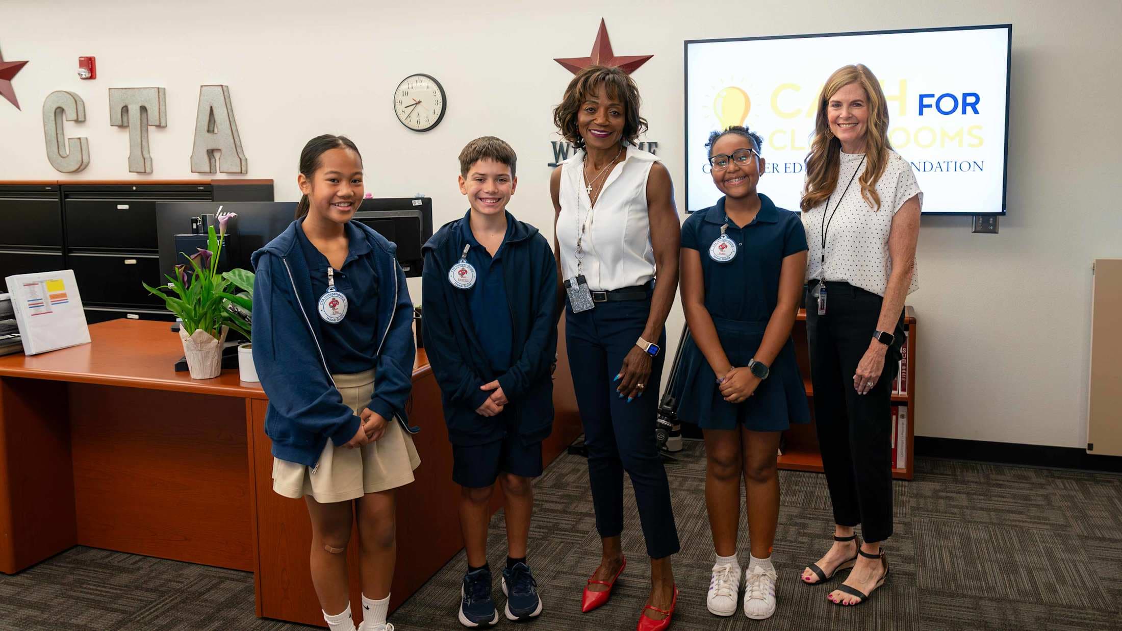 Dr. Anna Battle stands with Principal Lori Walter and three elementary school students.