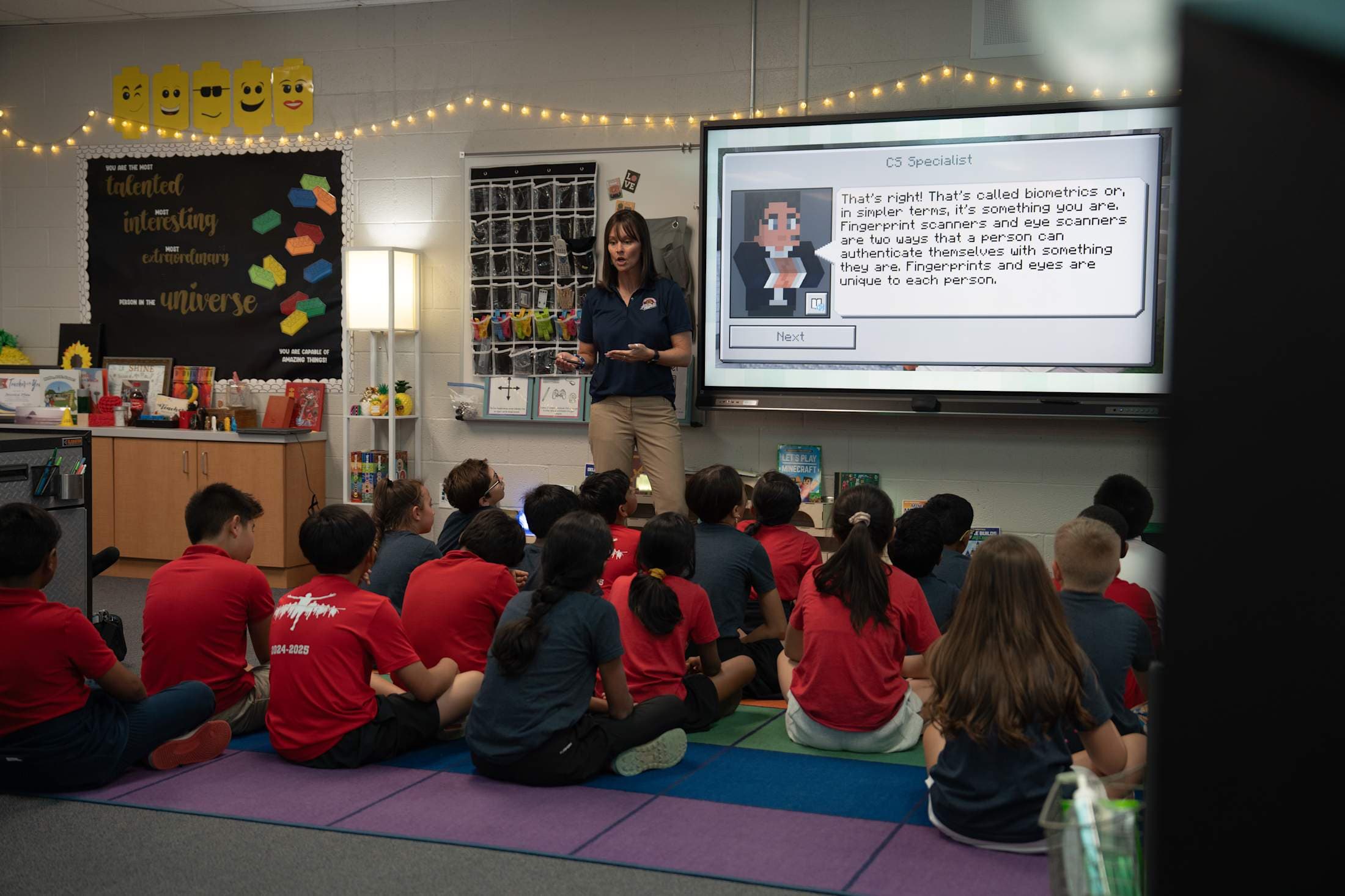 The technology teacher talks to a class full of students.