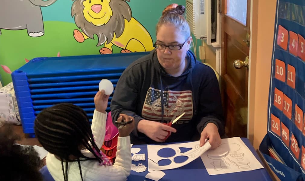 A student showing a circle cutted paper to the teacher