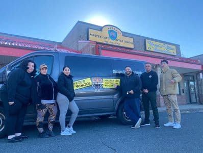 Group of people standing beside a van outside Master Lee's After School.