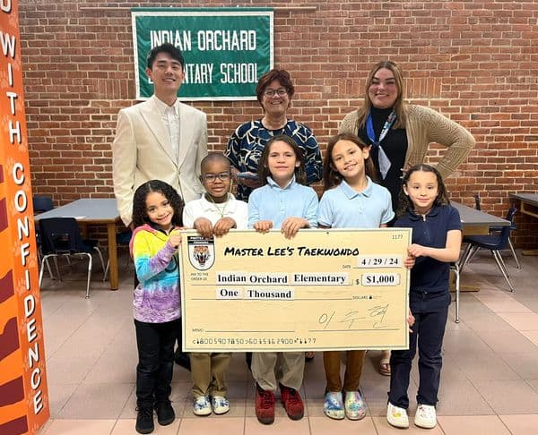 Students and staff at Indian Orchard Elementary hold a large $1,000 check from Master Lee's Taekwondo.