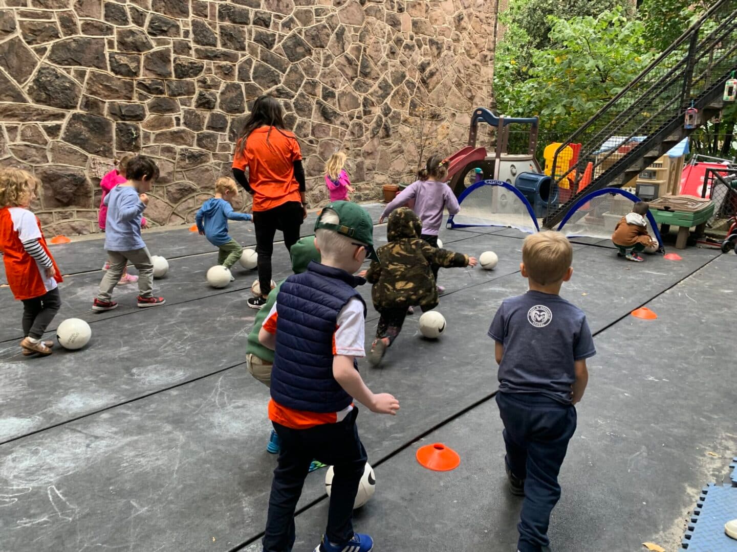 A group of children playing with balls on the ground.