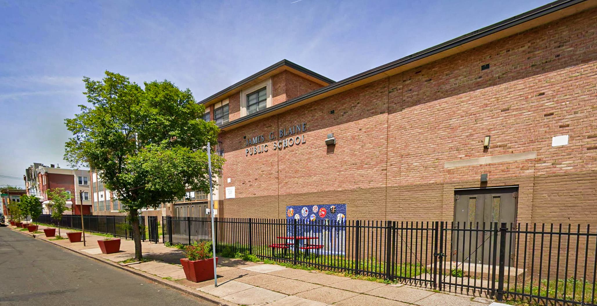 Exterior of James G. Blaine Public School in Philadelphia, showing the brick school building and fenced schoolyard.