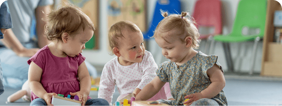 Three toddlers playing together with toys.