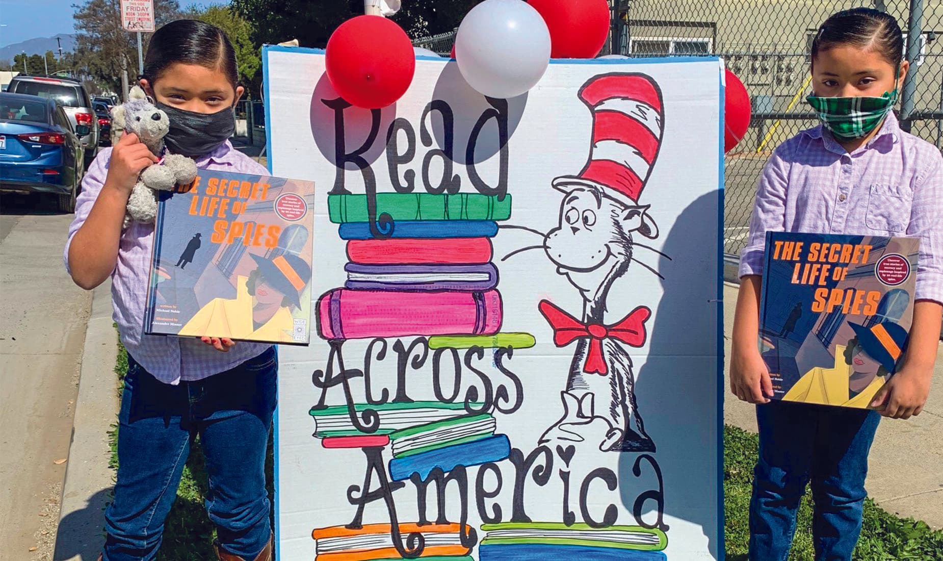 children holding books by Read Across America sign