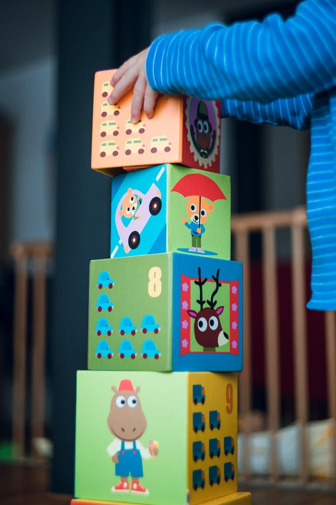 Michelle's Daycare and Preschool boy stacks funny animal comic cardboard boxes. Early childhood motor skills.