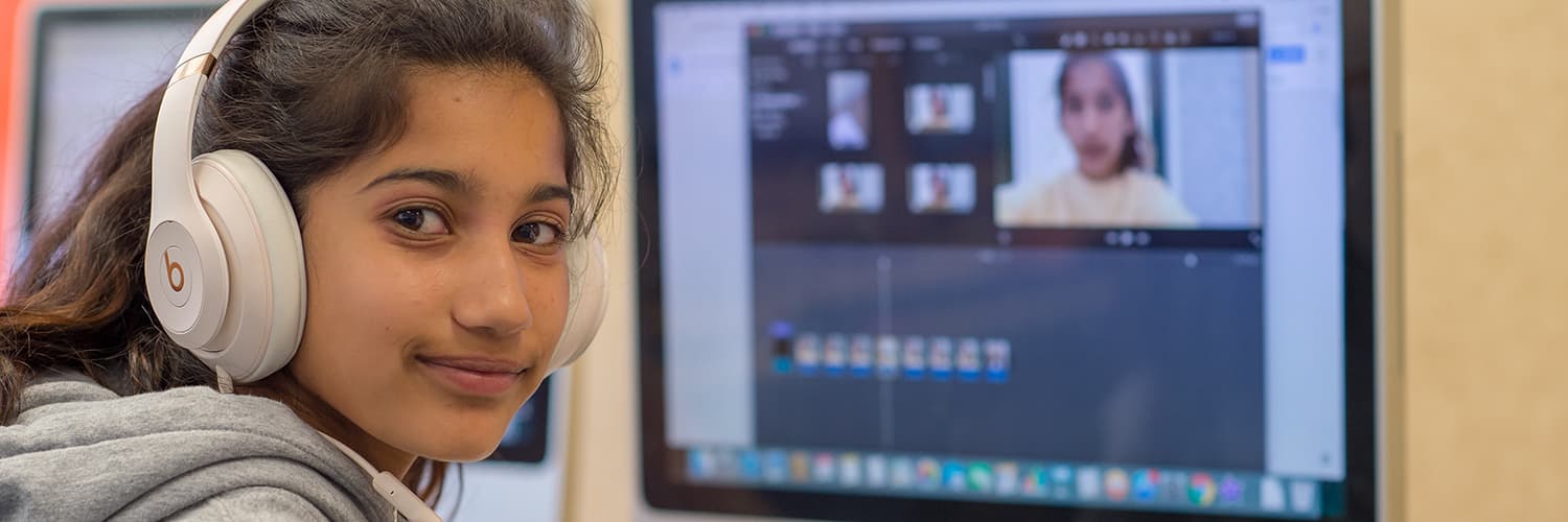 Girl working on a computer project with headphones on