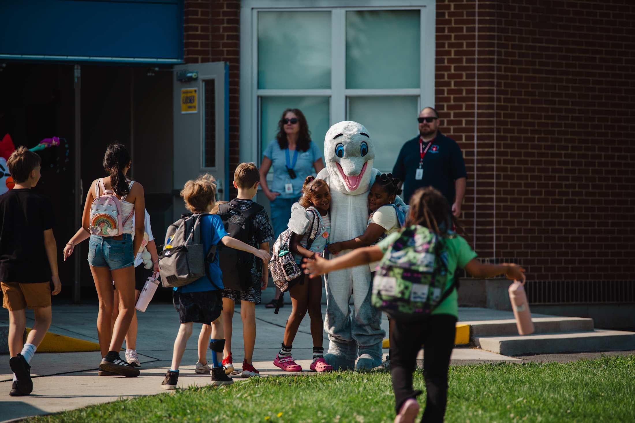 kids hugging a dolphin mascot