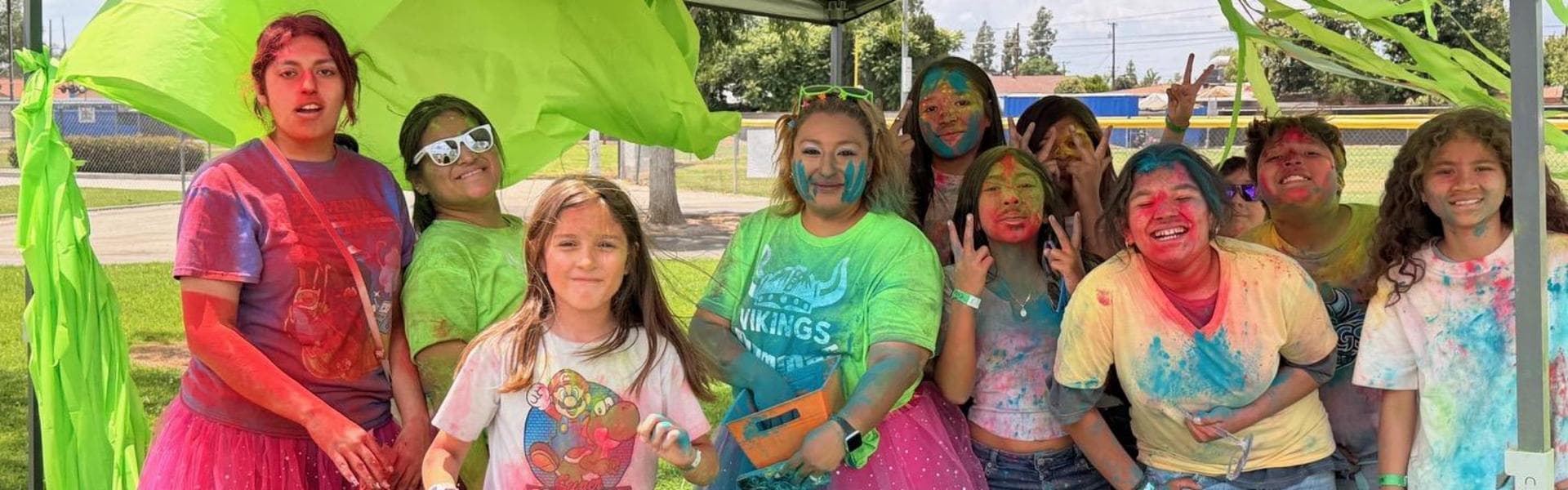 A group of children covered in colorful powder paint, smiling and posing together.