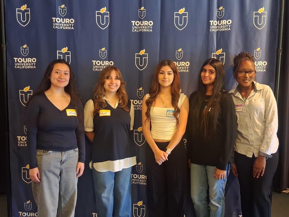5 FSUSD students posing in front of a Touro University backdrop