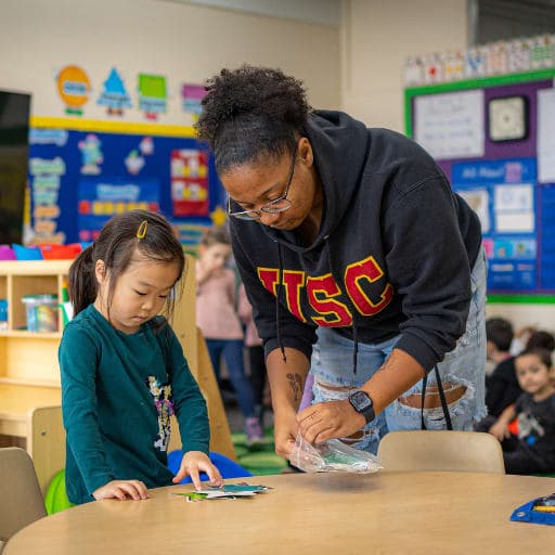Teacher working with young student at table