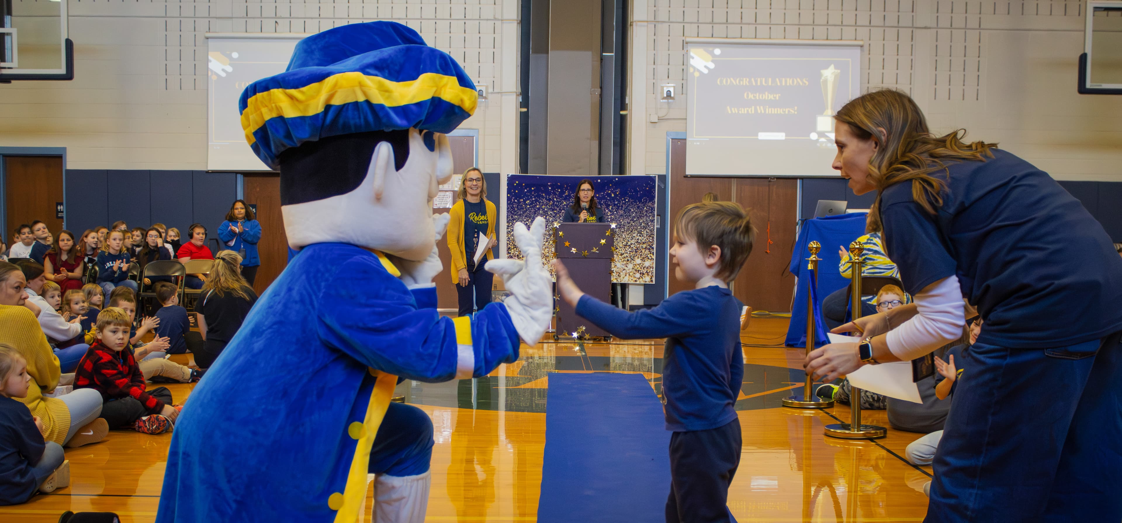 Rebel mascot high fives a student