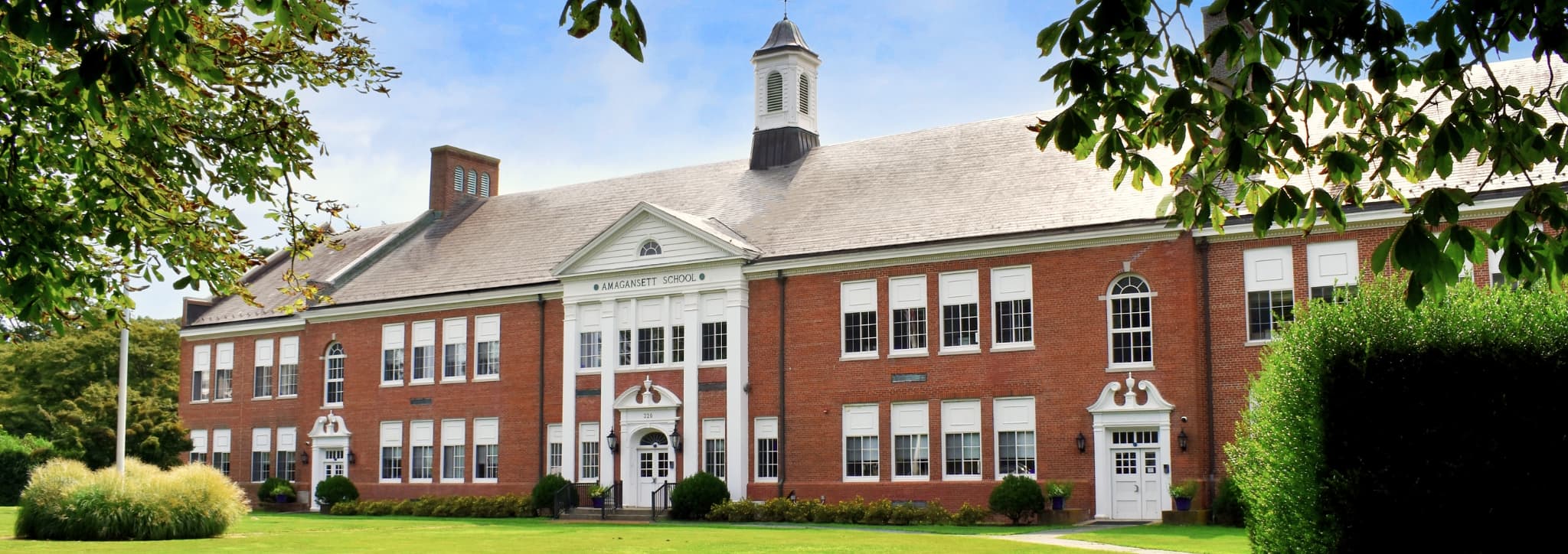 A brick building with a white trim and a green lawn.