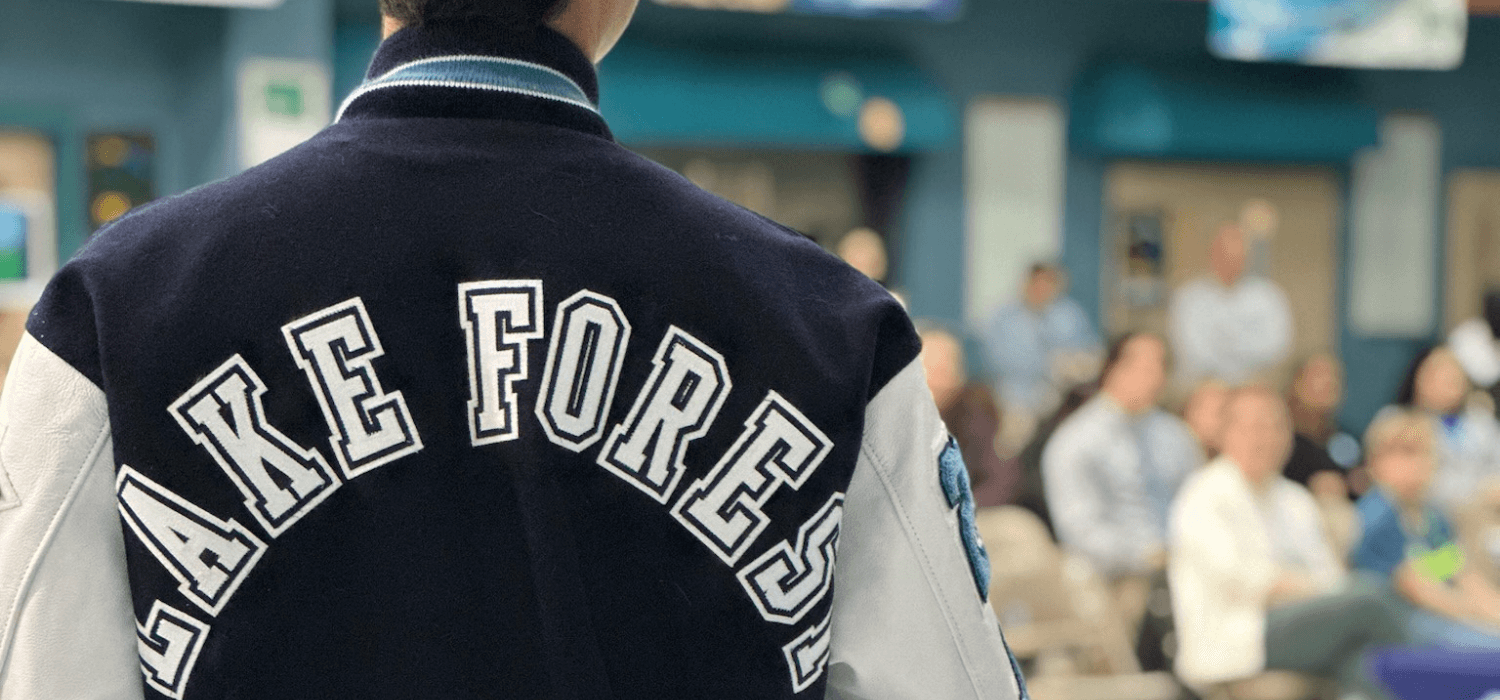 A person wearing a letterman jacket with 'FORE' visible on the back.