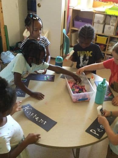 Children engaging in a craft activity around a table.