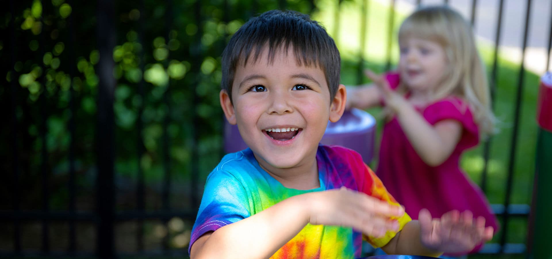 Child playing outdoor drums during a music activity at The Goddard School summer program.